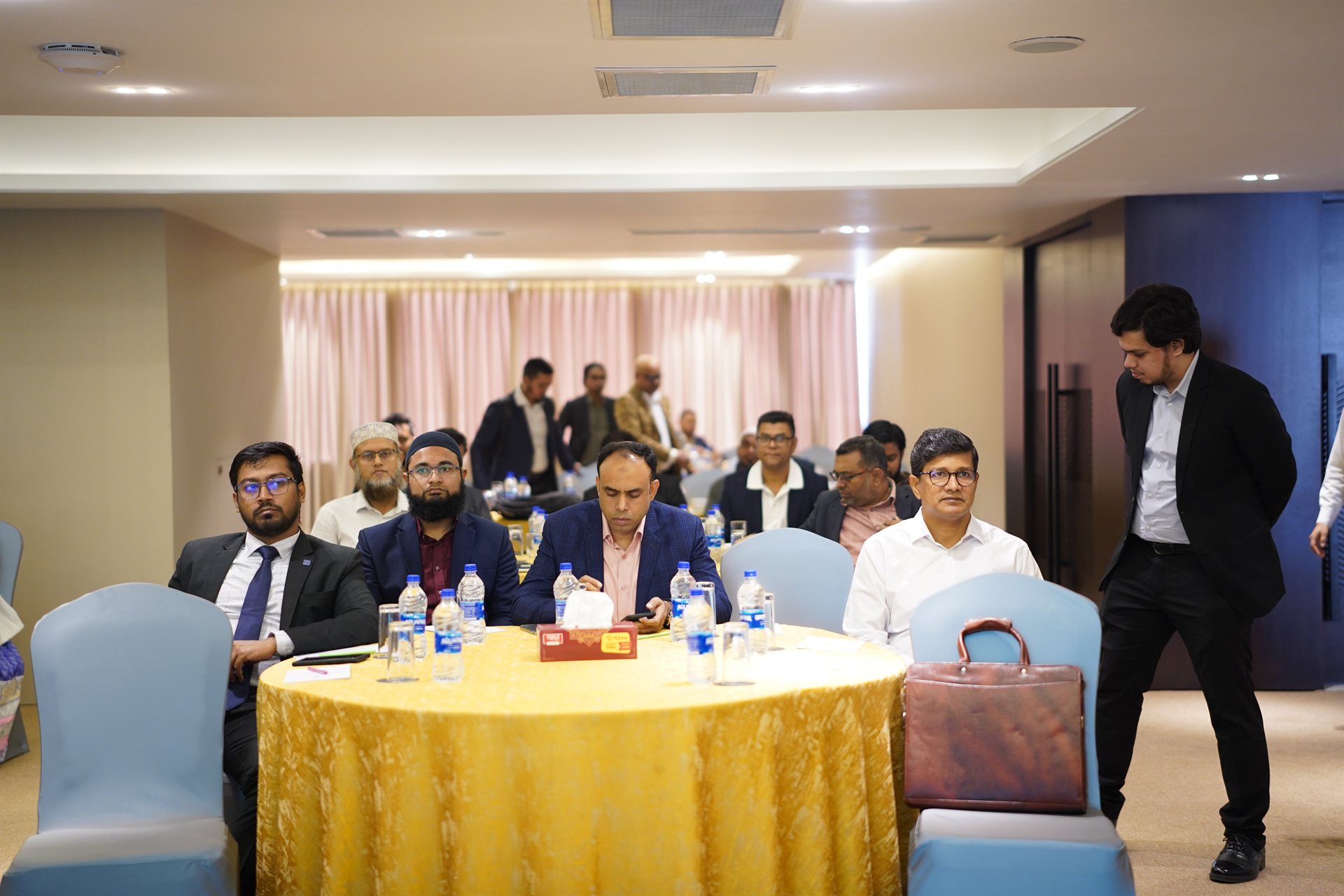 Workshop audience of consultants, factory representatives, and brand sourcing teams listening to the panel.